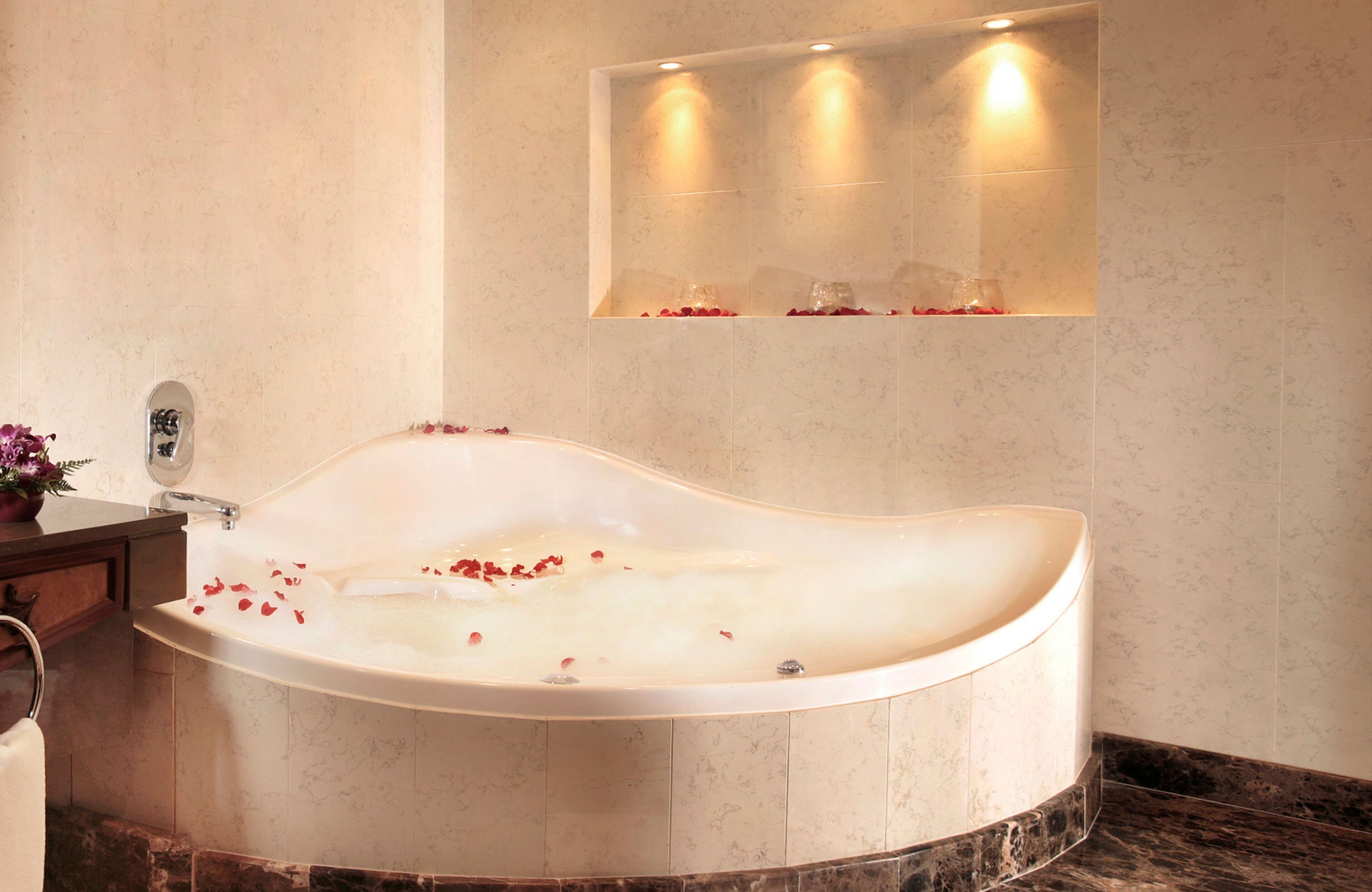 A modern bathroom with a freestanding bathtub, marble flooring, and a wall-mounted mirror.