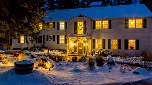 A two-story house with a porch, snow-covered ground, and a fire pit. - Sherwood Inn (Muskoka Lakes)