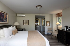 Ett hotellrum med en säng, ett nattduksbord, en lampa och ett skrivbord med en stol.