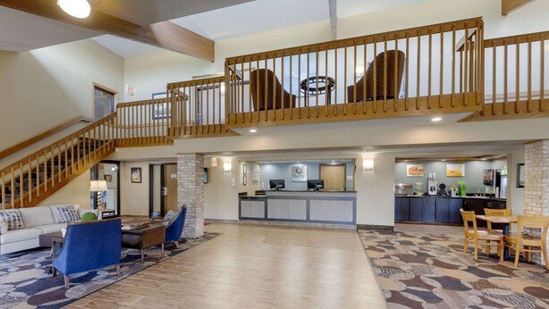 Amplia sala de estar con una escalera que conduce a un balcón, una zona de cocina y un mostrador de recepción.