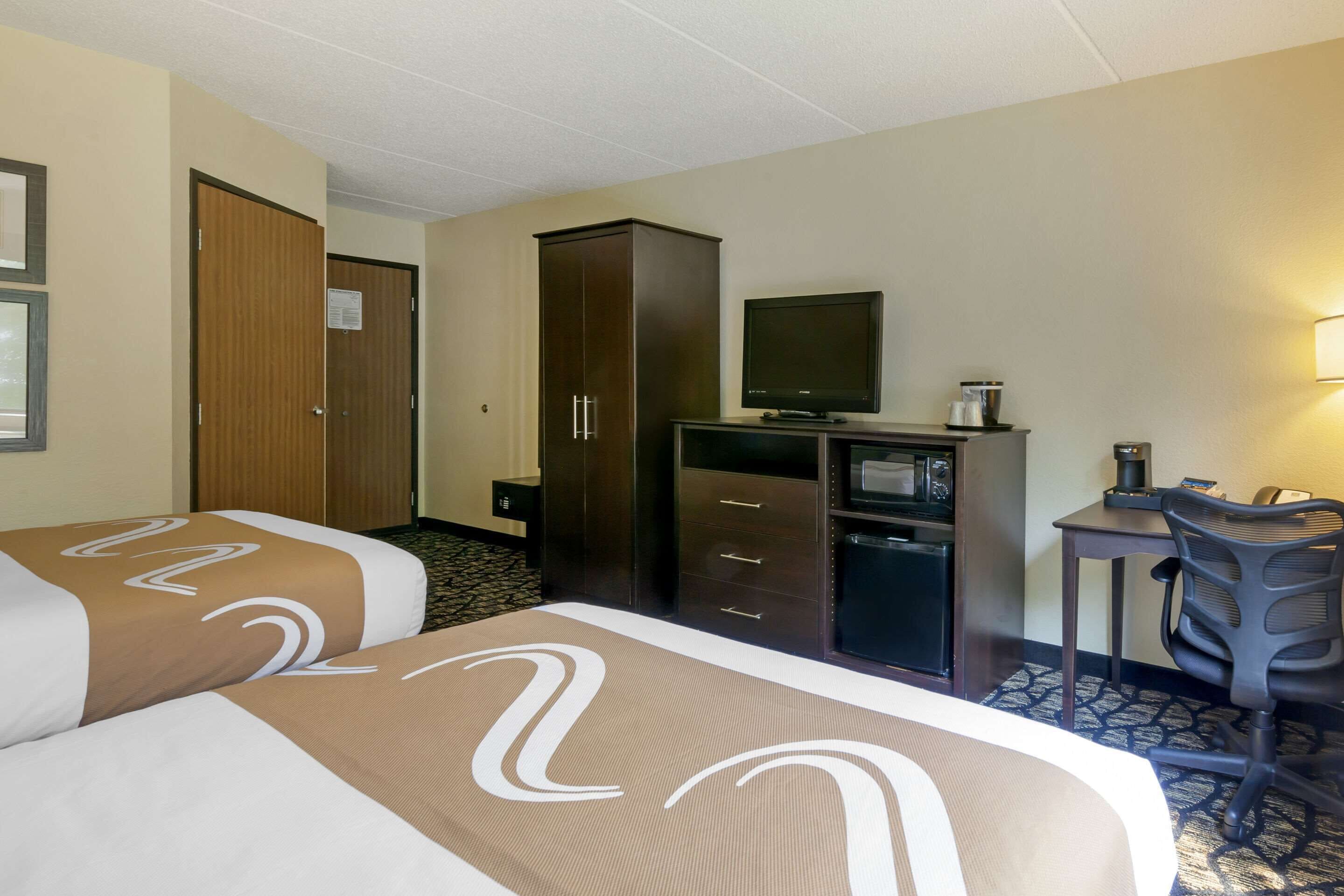 Una habitación de hotel con dos camas, un escritorio, televisión y un armario.