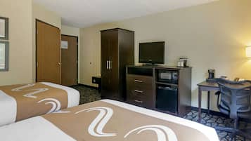 Una habitación de hotel con dos camas, un escritorio, televisión y un armario.