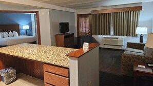 A hotel room with a bed, a desk, a chair, a TV, and a small kitchenette. - AmericInn by Wyndham Marshall (Marshall)