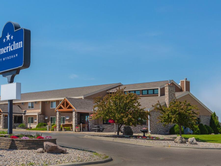 A hotel with a prominent sign, a well-maintained lawn, and a clear sky.