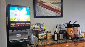 A coffee station with a beverage dispenser, coffee makers, and a framed historical document on the wall.