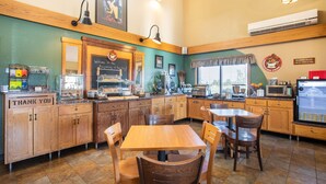 A restaurant with wooden cabinets, a chalkboard menu, and a breakfast counter. - AmericInn by Wyndham Marshall (Marshall)
