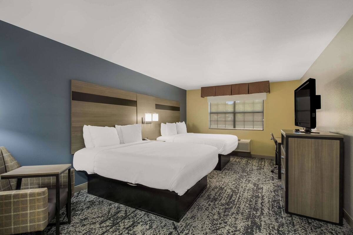 Ein Hotelzimmer mit einem großen Bett, einem Schreibtisch, einem Sessel, einem Fernseher und einem Fenster.