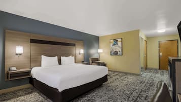 A hotel room with a large bed, bedside tables, a desk, a chair, and a painting on the wall.