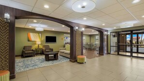 A lobby with a seating area, a television, and a large glass door leading outside.
