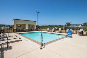 A swimming pool with lounge chairs and a covered seating area.