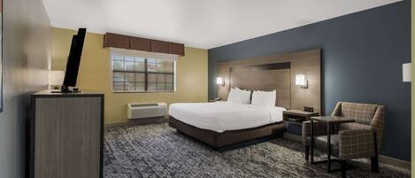 A hotel room with a bed, a desk, a chair, and a large window.