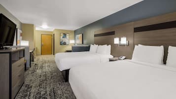 Una habitación de hotel con dos camas, un escritorio con televisor y piso alfombrado.