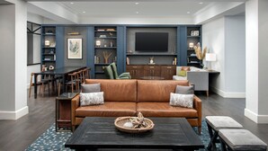 Ein modernes Wohnzimmer mit einer Ledersofa, einem Essbereich mit Tisch und Stühlen, einem an der Wand montierten Flachbildfernseher und einer Kristallleuchtre.