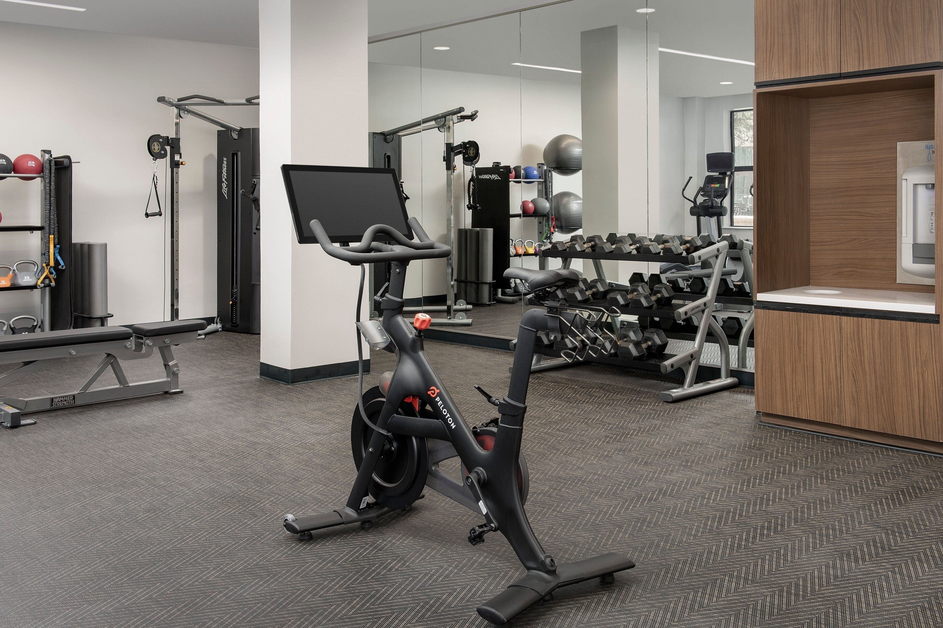 Une salle de sport équipée de matériel d’exercice, de poids et d’un miroir.