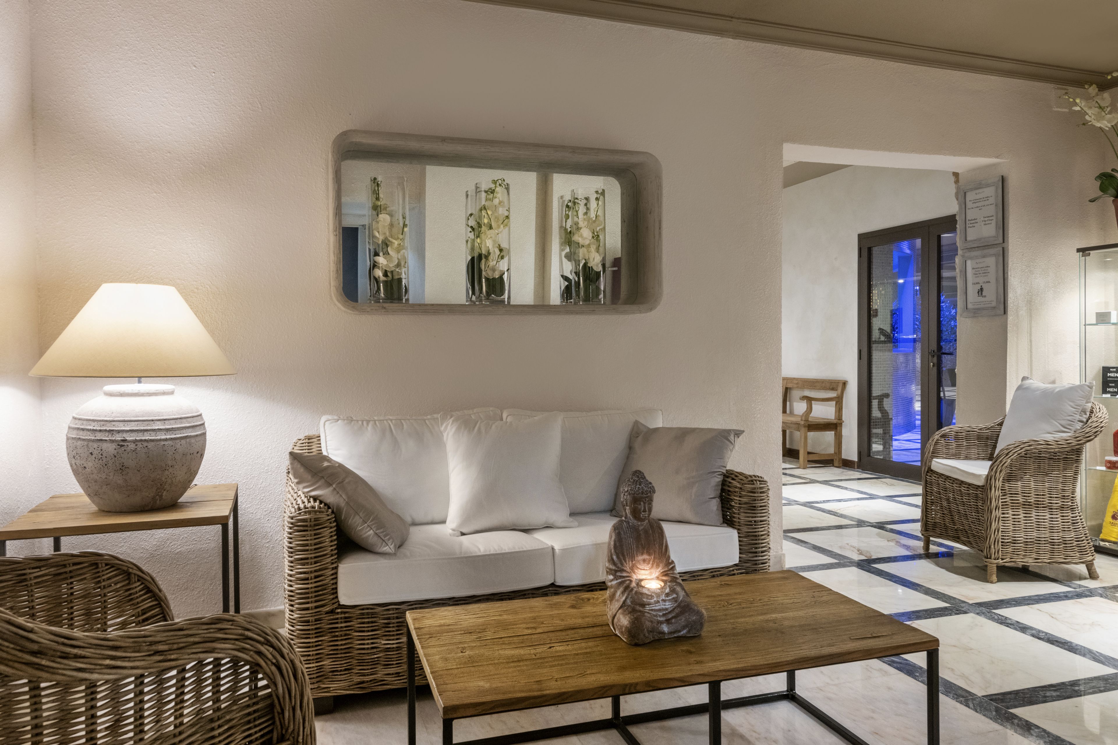 A modern living room with a sofa, two wicker chairs, a coffee table, and a lamp.