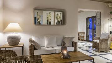 Ein modernes Wohnzimmer mit einer Couch, zwei Korbstühlen, einem Couchtisch und einer Lampe.