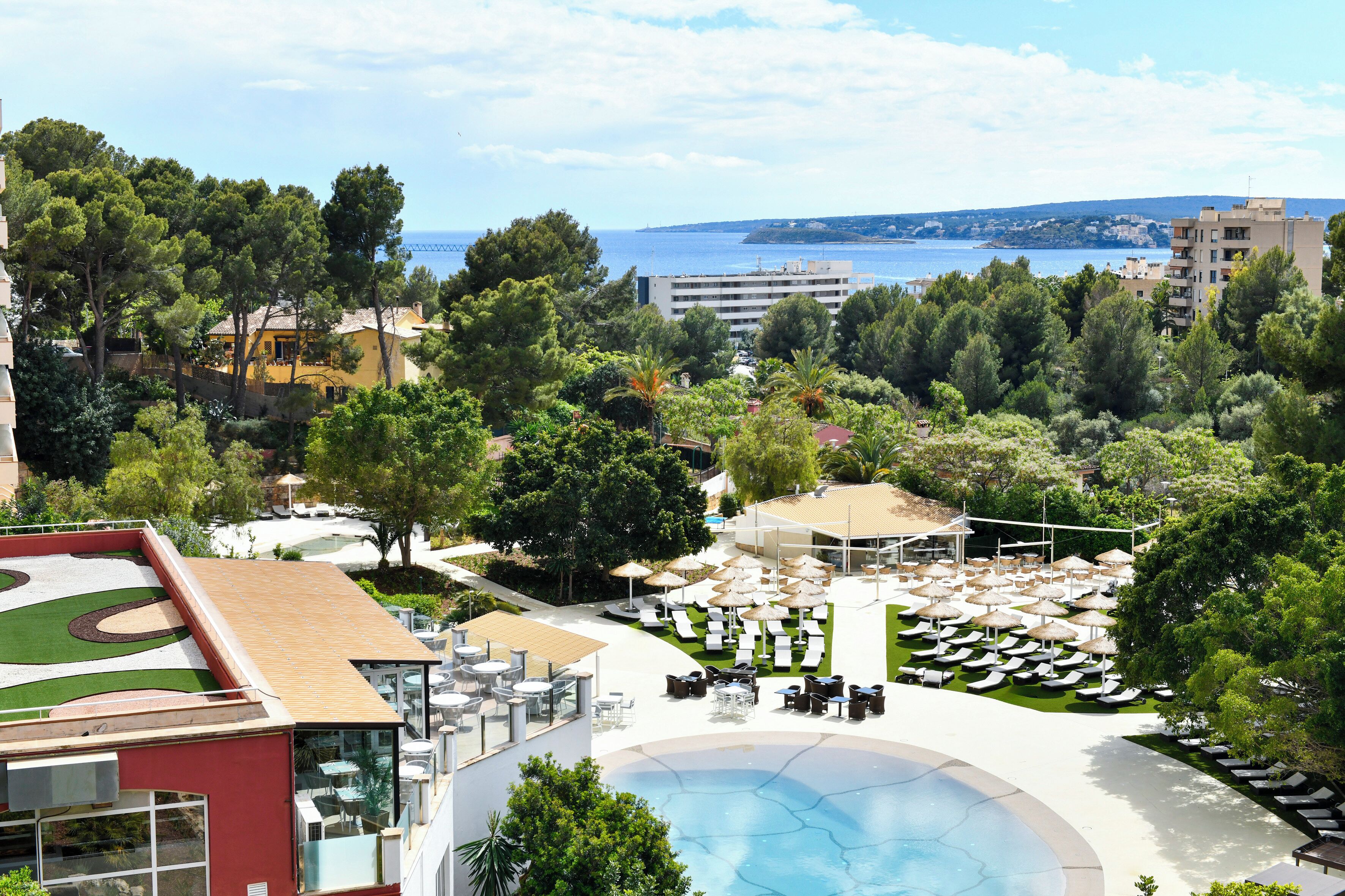 Et resort med swimmingpool, liggestole og havudsigt.