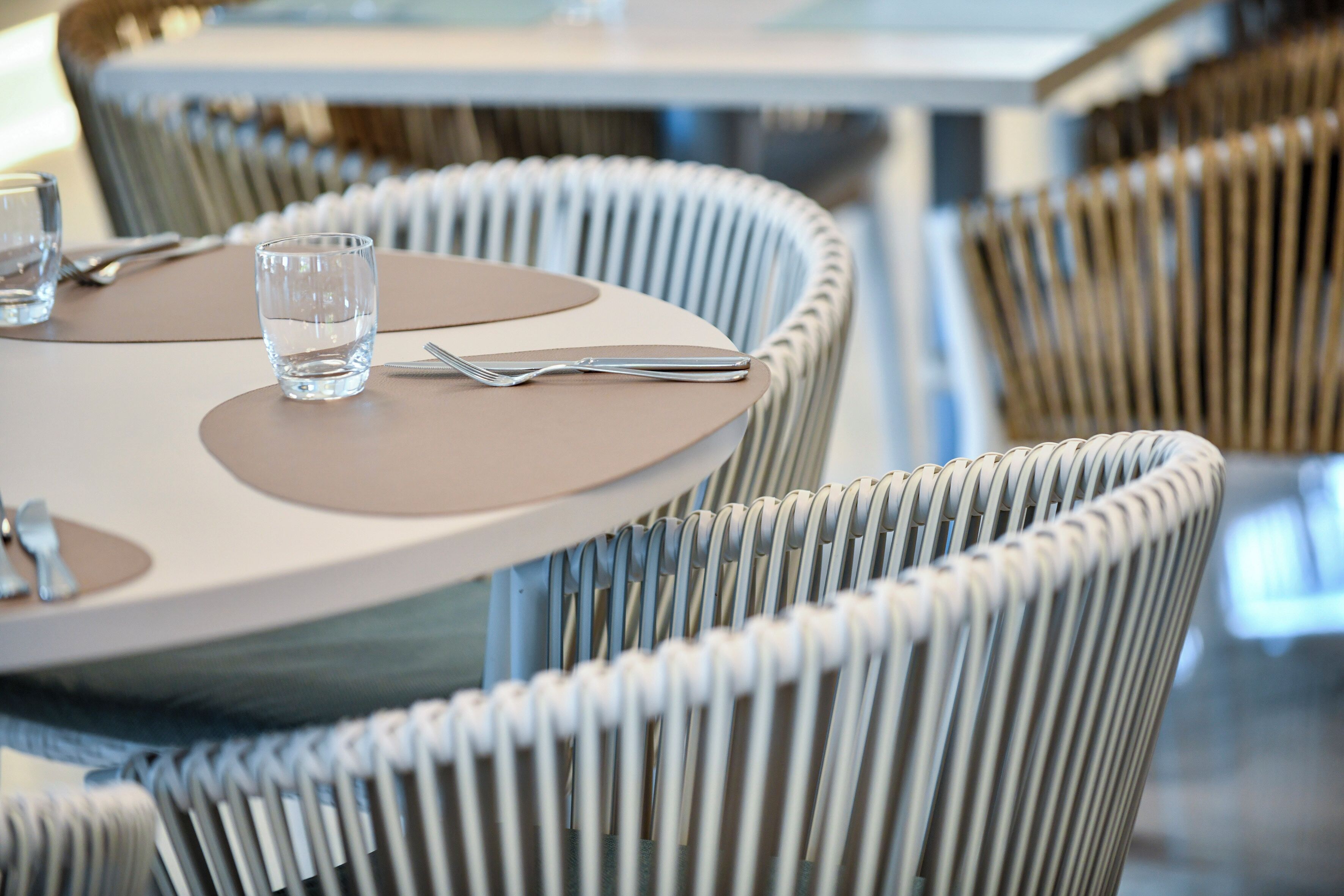 A dining area with round tables and wicker chairs.