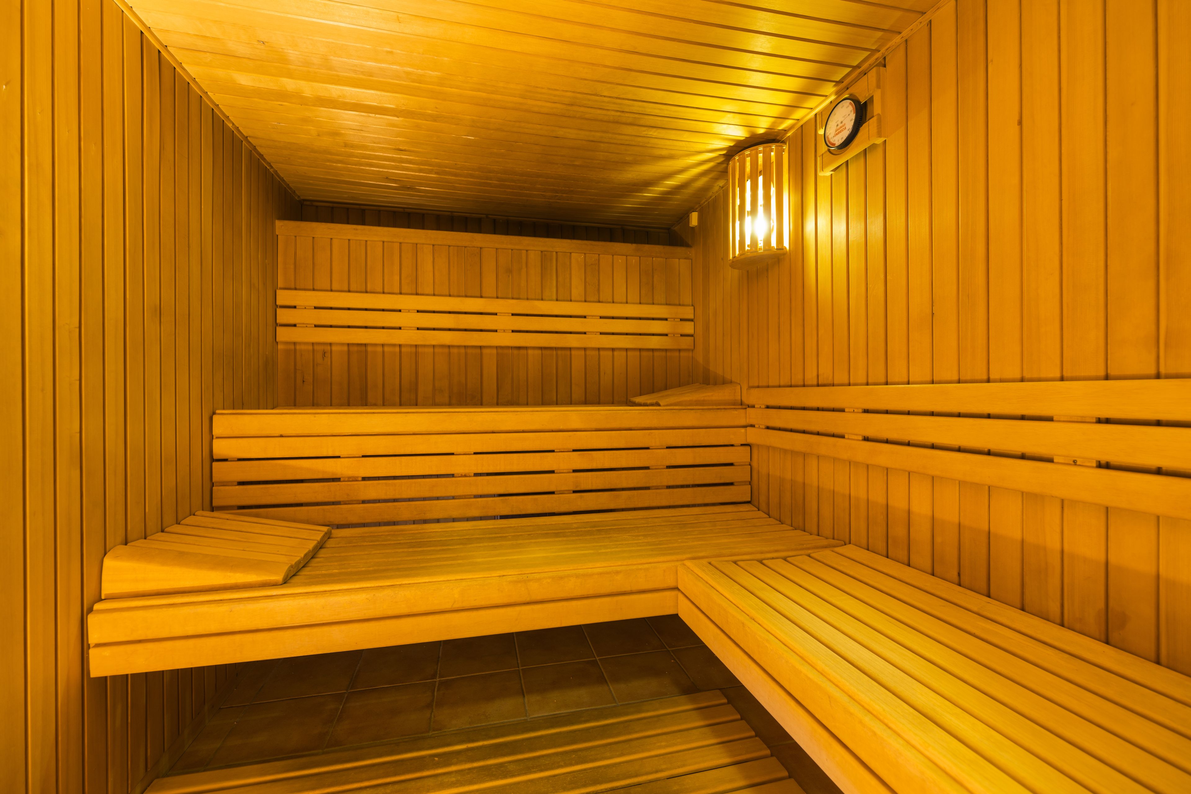 A sauna with wooden benches and a clock on the wall.