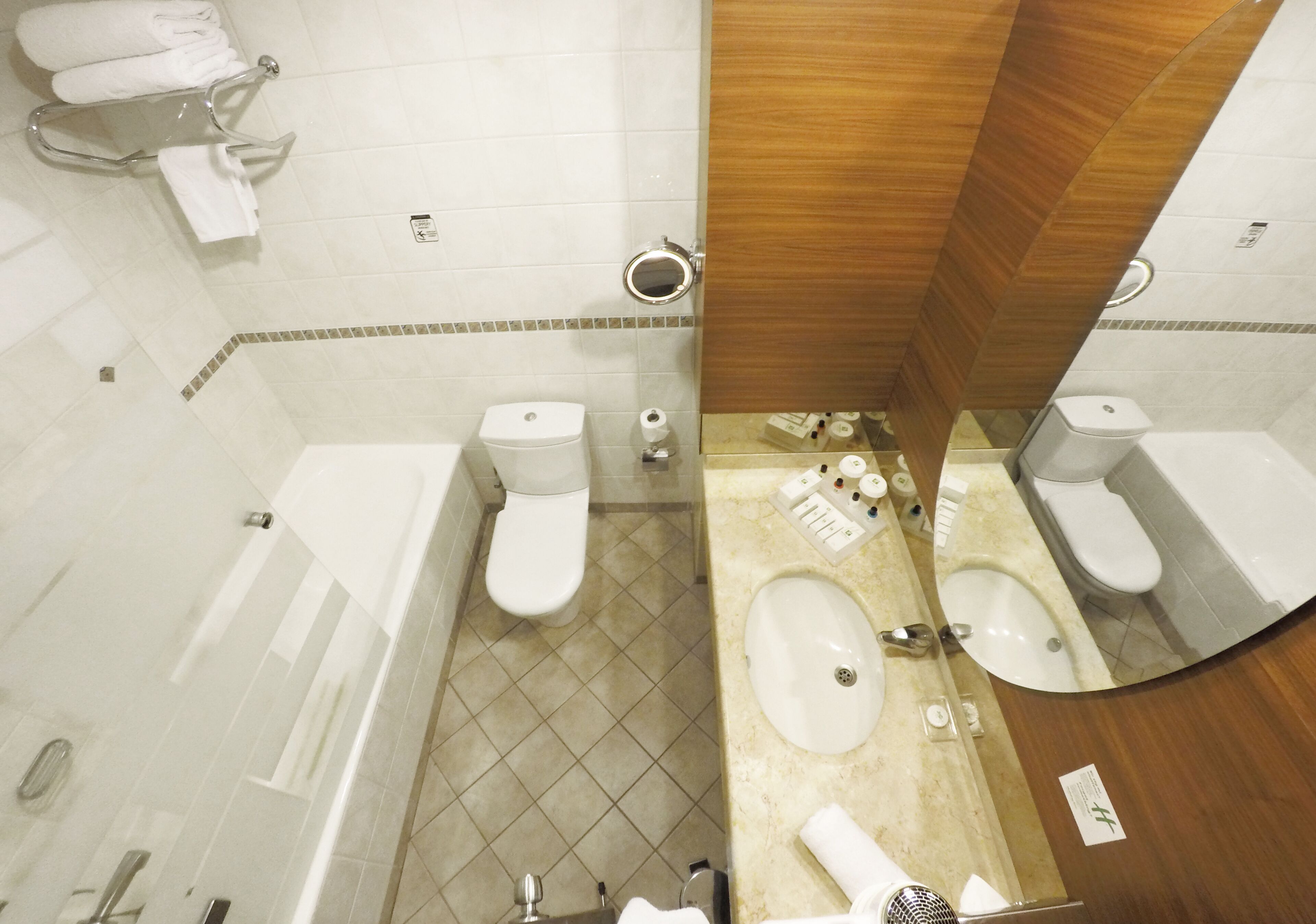 A bathroom with a bathtub, two toilets, a sink, and a mirror.