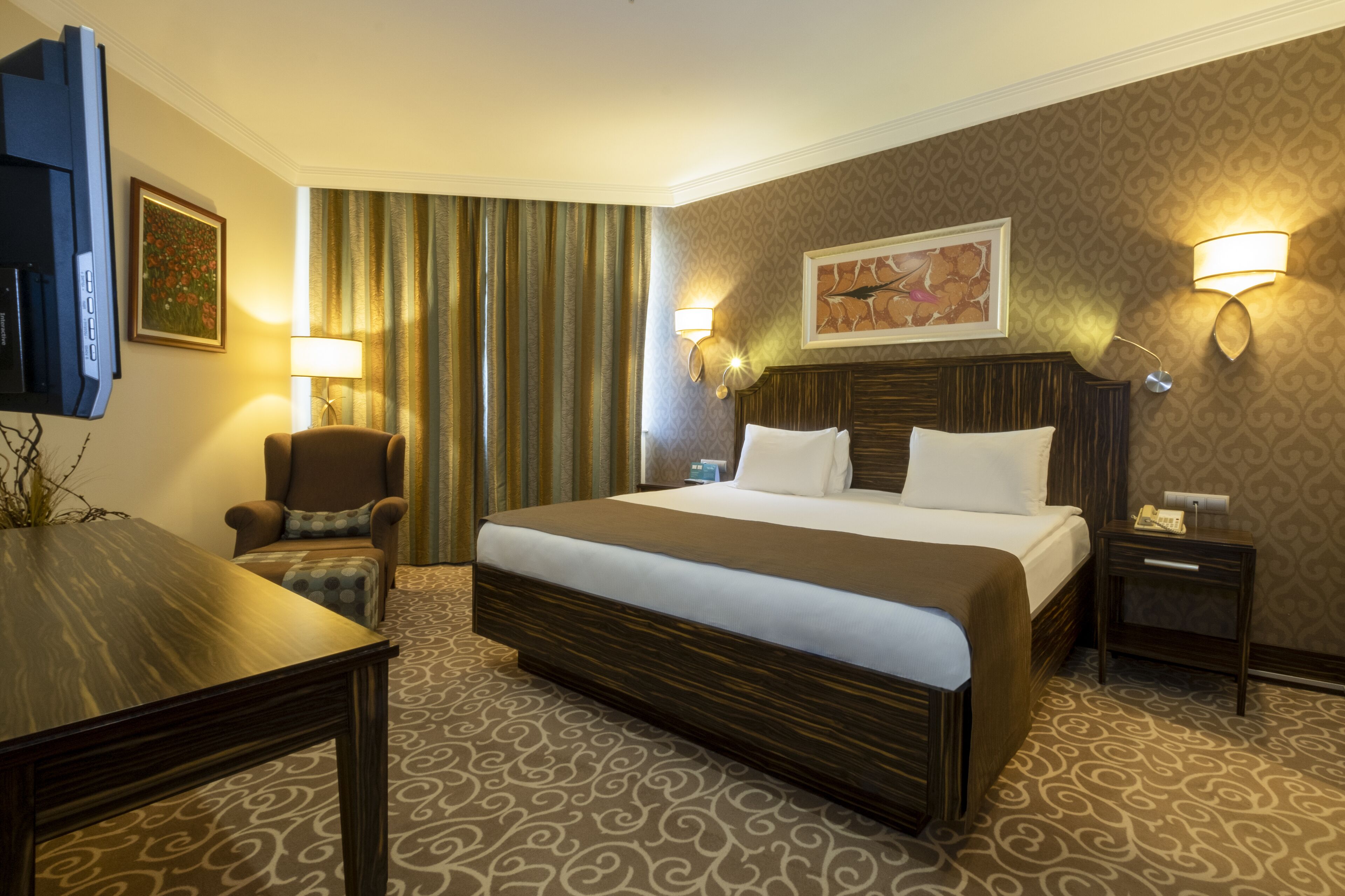 Une chambre d’hôtel avec un grand lit, une chaise, un bureau et une télévision.