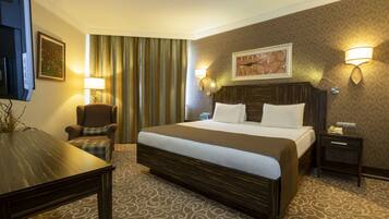 Une chambre d’hôtel avec un grand lit, une chaise, un bureau et une télévision.