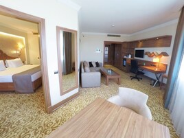 Una habitación de hotel con cama, sofá, escritorio y televisor.