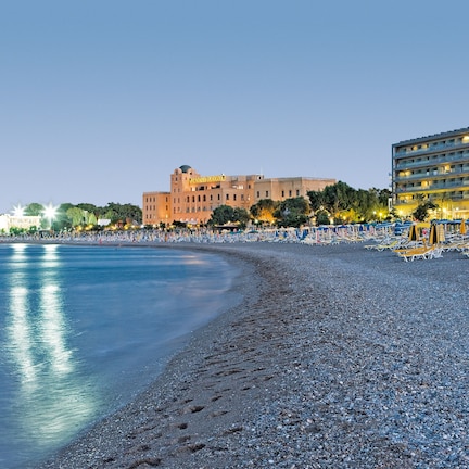 A beachside hotel with a large building and a smaller structure in the background.