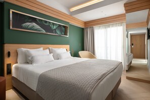A modern hotel room with a large bed, a wooden headboard, a green accent wall, and a large window with curtains. - Hotel Mediterranean (Rhodes)