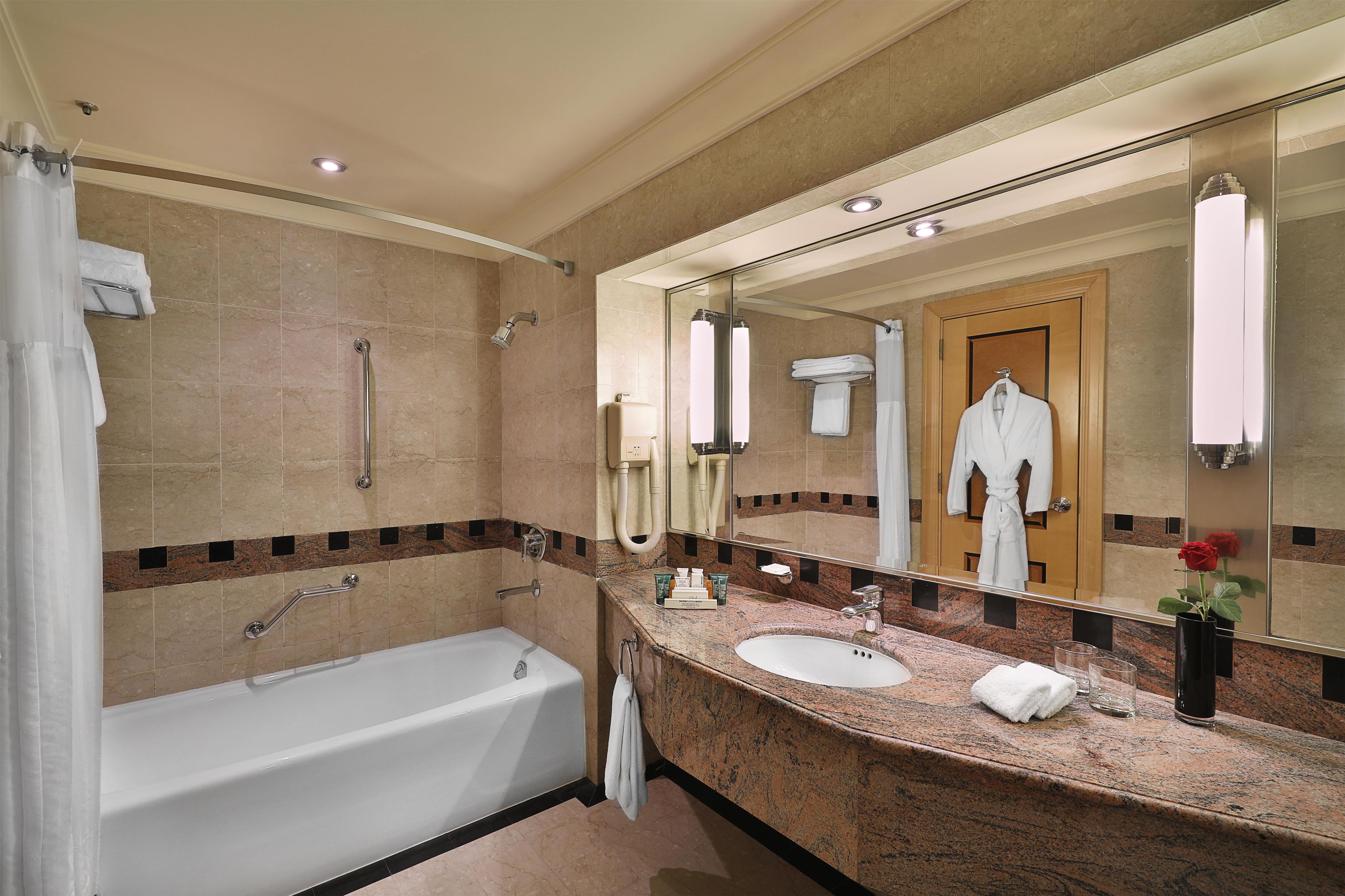 A modern bathroom with a bathtub, a sink, and a large mirror.