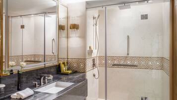 A modern bathroom with a large mirror, a marble sink, and a glass-enclosed shower area.
