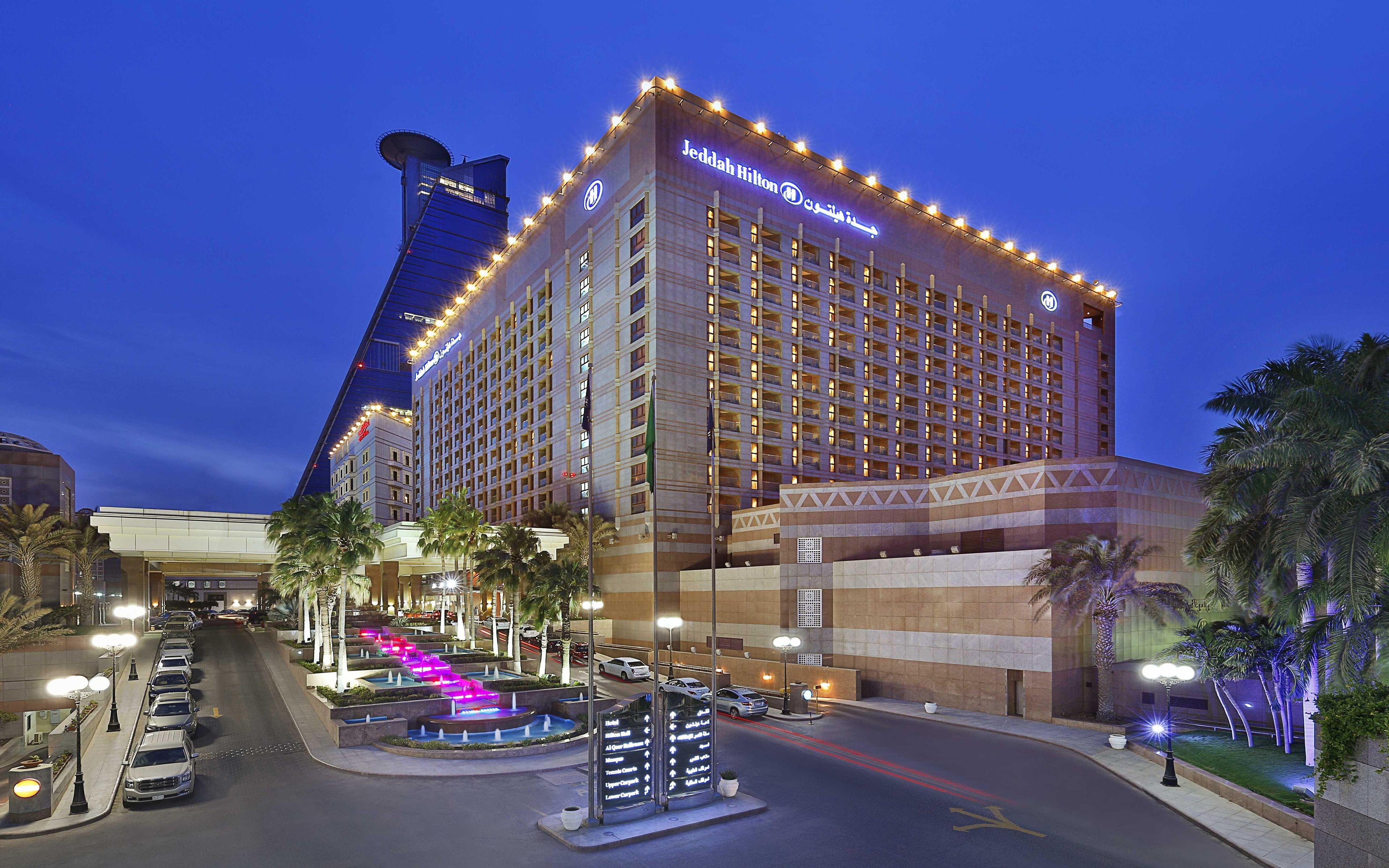 Un hotel con una torre destacada, varios pisos y una entrada bien iluminada.