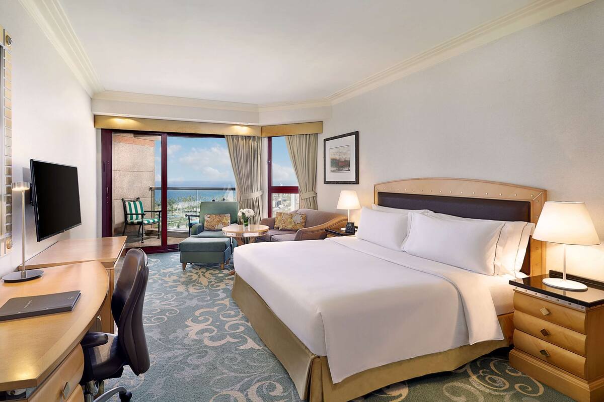 A hotel room with a bed, desk, chair, and a TV.