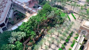 An aerial view of a landscaped area with palm trees, a water feature, and modern buildings. - Jeddah Hilton (Jeddah)