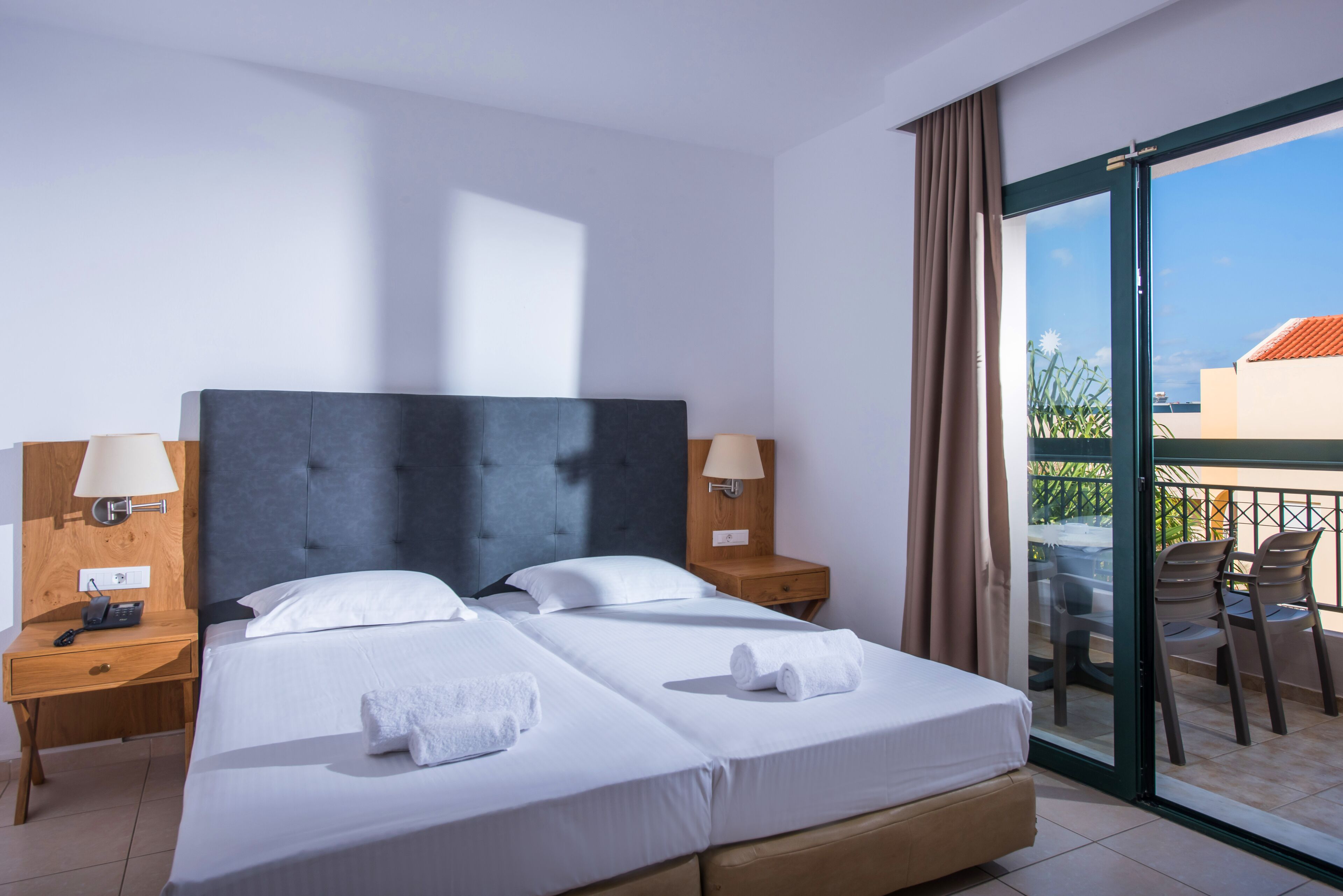 A hotel room with two beds, a balcony, and a view of the city.