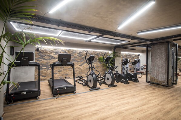 A gym with treadmills, stationary bikes, and a wall with a brick pattern.