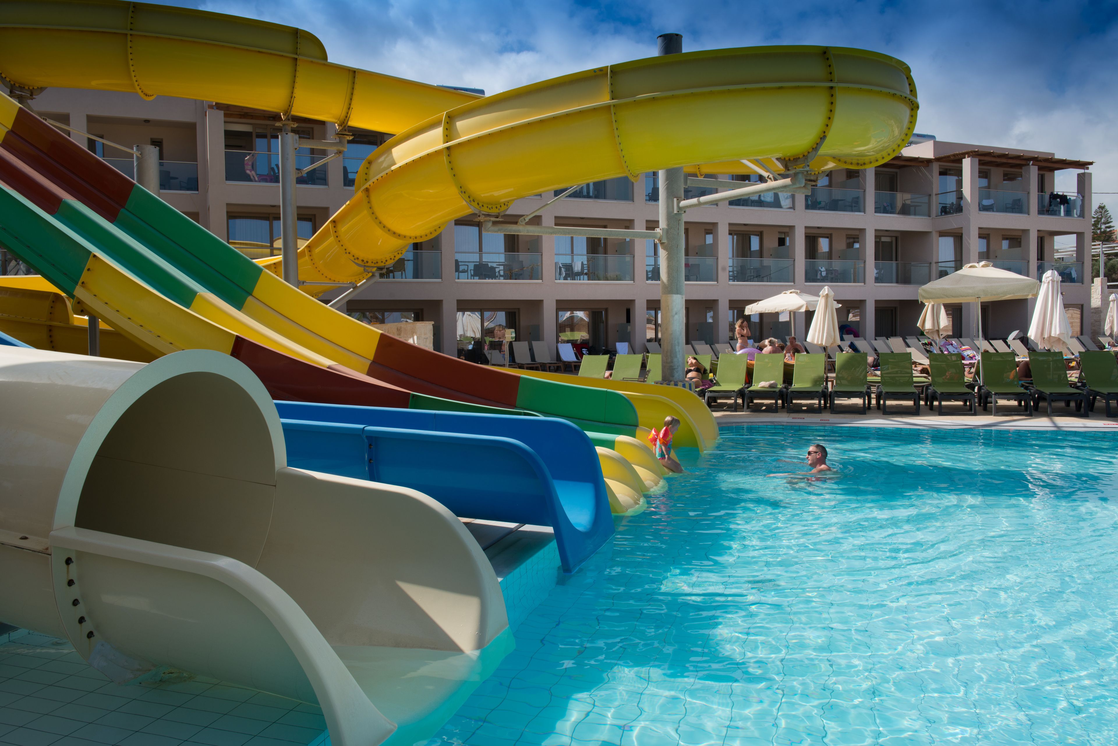 A swimming pool with multiple slides and lounge chairs.