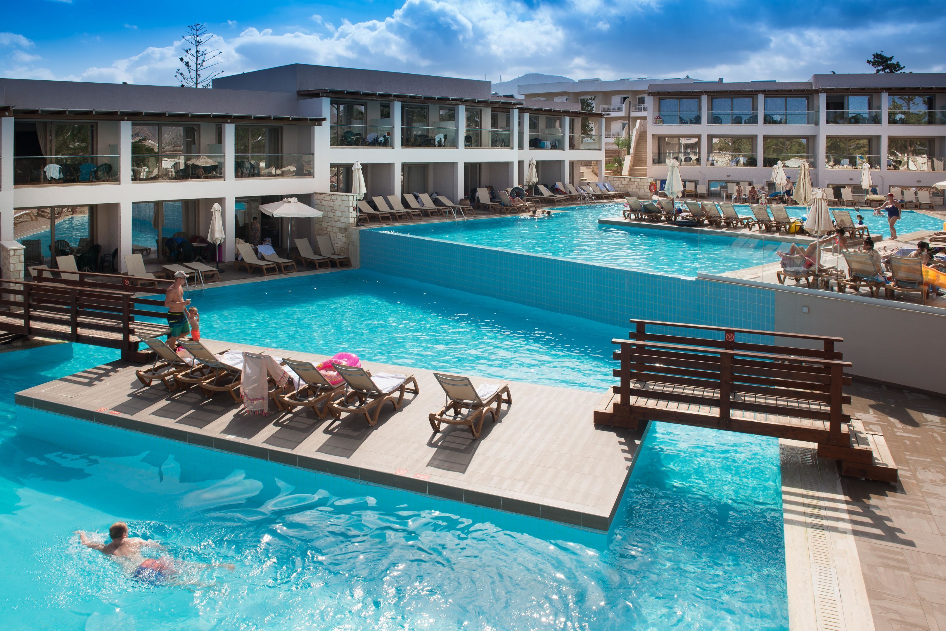 A large indoor swimming pool with multiple levels of balconies, lounge chairs, and umbrellas.