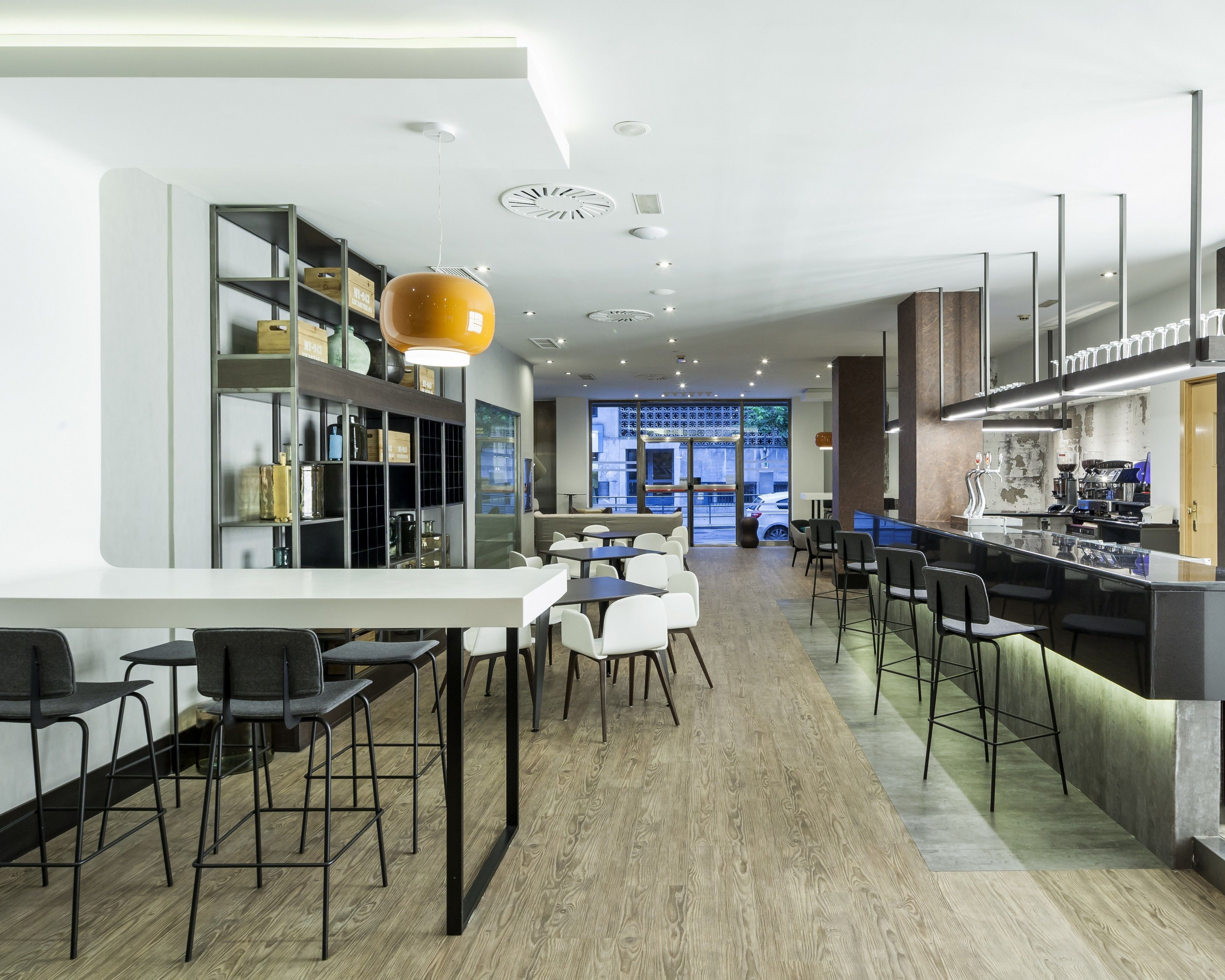 Een modern restaurant met een bar, witte stoelen en een houten vloer.