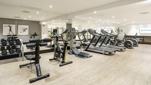 A modern gym with various exercise equipment, including treadmills and weight machines, and a display of dumbbells. - Hotel ILUNION Bilbao (Bilbao)