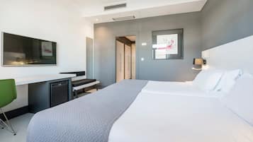 Una habitación de hotel moderna con una cama, un escritorio, una silla y una kitchenette pequeña.