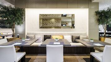Un comedor moderno con una mesa larga, sillas blancas y una zona de estar central con cojines.