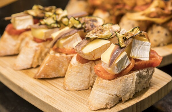 Una tabla de madera con varias rebanadas de pan cubiertas de tomates, queso y posiblemente nueces.