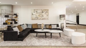 A modern living room with a sectional sofa, a round coffee table, and a minimalist design. - Hotel ILUNION Bilbao (Bilbao)