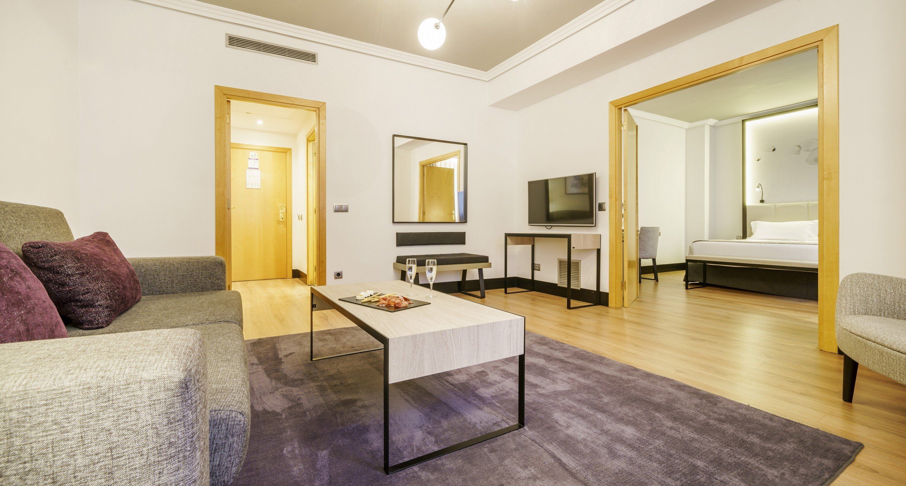 Una sala moderna con un sofá, una mesa de centro, un televisor y una cama.