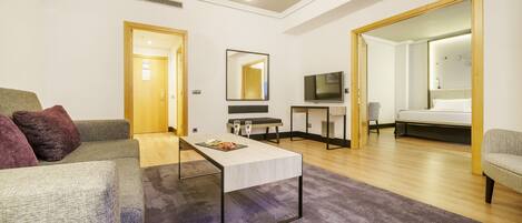 Una sala moderna con un sofá, una mesa de centro, un televisor y una cama.