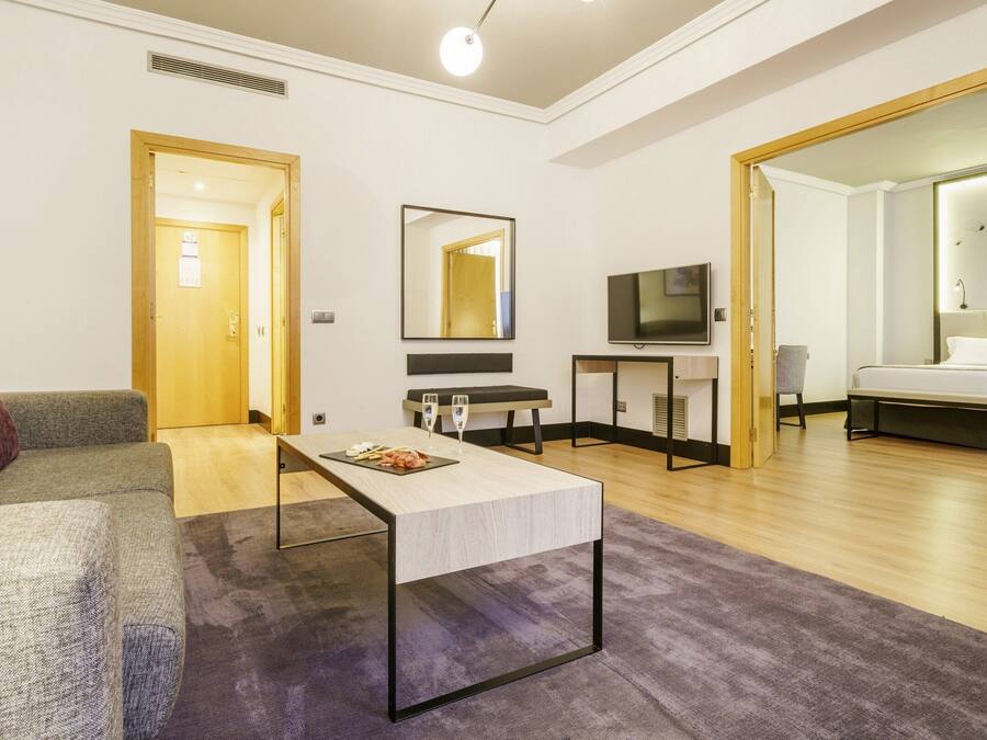 Una sala moderna con un sofá, una mesa de centro, un televisor y una cama.