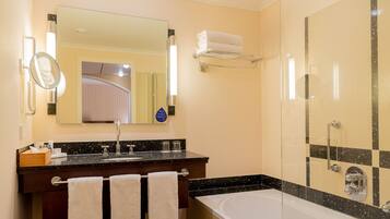 A modern bathroom with a large mirror, a sink, a bathtub, and a shower area.