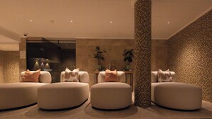 A modern, well-lit lobby with three round seating areas, a central column, and a patterned wall.