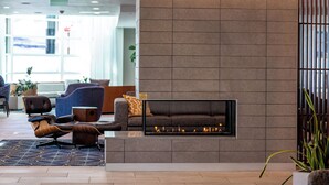 A modern lobby with a fireplace, seating area, and a view of the outside. - River's Edge Hotel Portland, Tapestry Collection by Hilton (Portland)